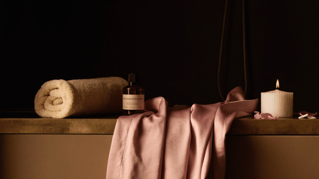 Entretien des sextoys : nettoyant et flacon posés dans une salle de bain feutrée aux tons prune et laiton